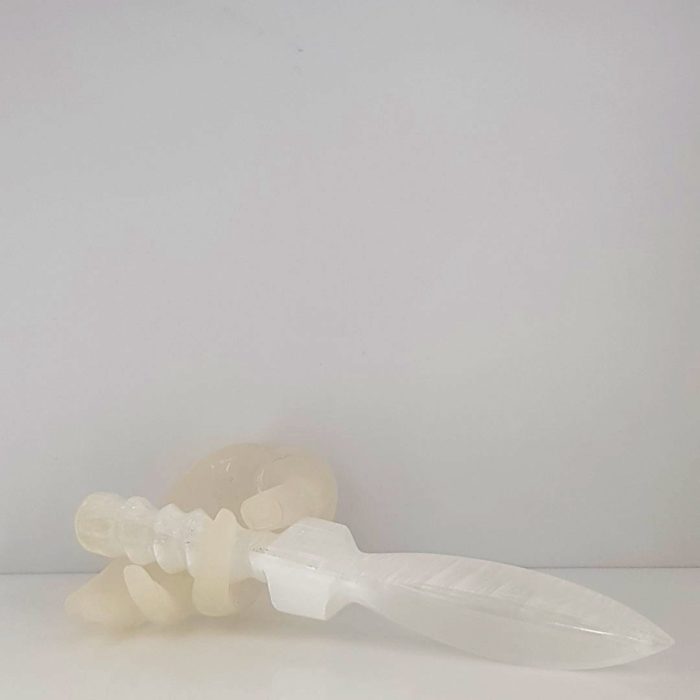 A white plastic knife, also known as a Selenite Sword, sitting on a white surface.
