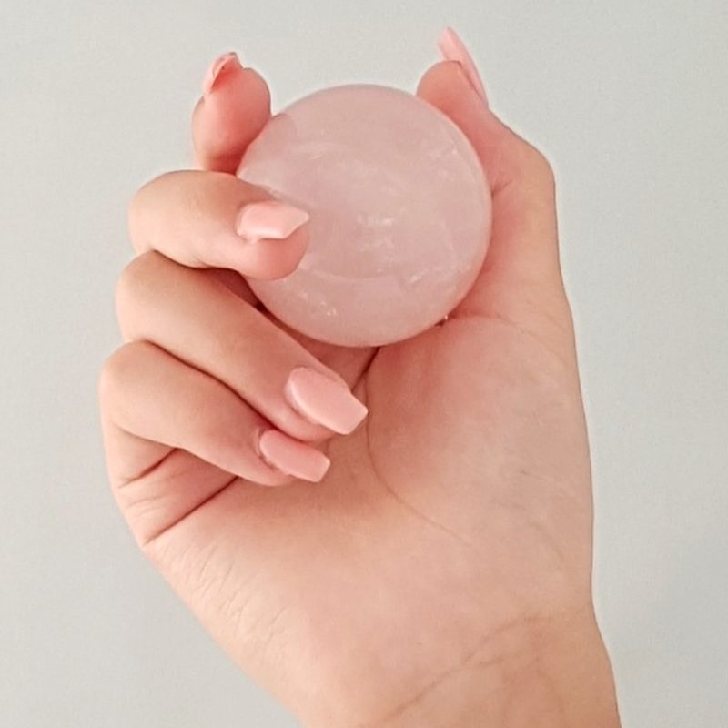 A person holding a Rose Quartz Solid Ball.
