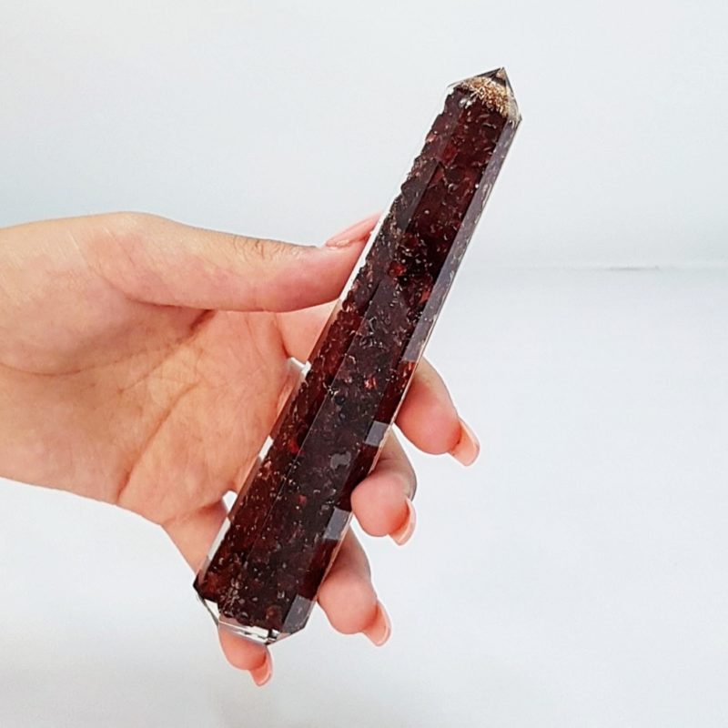 A person holding a piece of red quartz in their hand.
