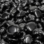 A pile of Black Obsidian Tumbled Crystals in a black and white photo.